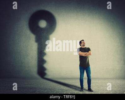 Sicher Mann, hält die Arme verschränkt, Gießen ein Schatten an der Wand. Ehrgeiz und Erfolg. Motivation und innere Stärke Symbol. Stockfoto