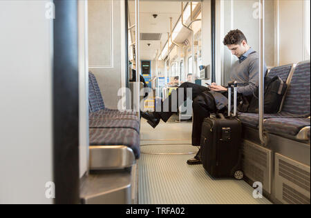 Unternehmer Business Reisenden Pendler mit Rolle Tasche Koffer mit Handy Gepäck auf der U-Bahn Stockfoto