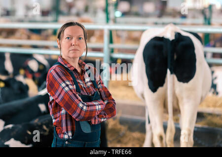 Frau Bauer im Kuhstall auf einem milchviehbestand Farm, Portrait von zufriedenen stolz Cowgirl mit ihrem Vieh in Ranch Scheune Stockfoto