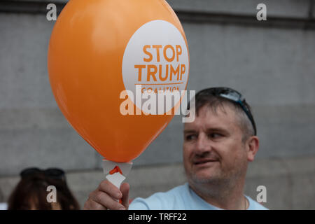 London, Großbritannien. Juni 2019. Ein Protestler hält einen Ballon mit Stop Trump Koalition, einer von vielen Demonstranten, die einen Protesttag im Zentrum von London am Trafalgar Square gegen den Präsidenten der USA, Donald Trump, halten, der Großbritannien besucht. Bild: Joe Kuis / Alamy Stockfoto
