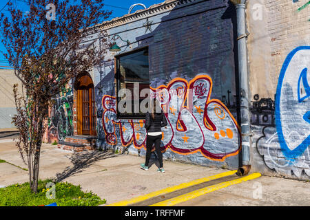 Frau Hinunter eine einsame Graffiti laden Straße in Red Hook in Brooklyn, New York Stockfoto