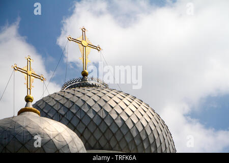 Nahaufnahme der zwei Kuppeln der Kirche mit goldenen Kreuzen gegen den blauen Himmel mit Wolken, Weichzeichner, Copyspace Stockfoto