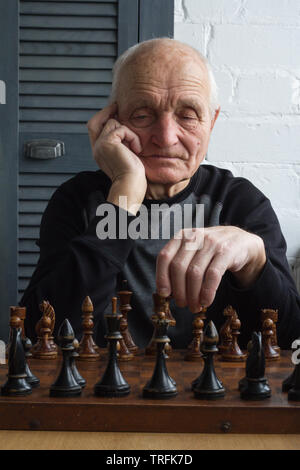 Ein alter Mann sitzt vor einem Schachbrett, Denken und machen Sie den ersten Schritt in das Spiel, Copyspace Stockfoto