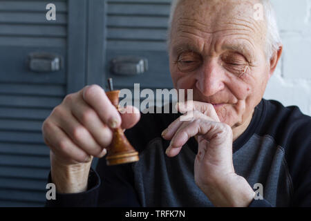 Der alte Mann hält in seinen Händen die Schachfigur des Königs, das Konzept von Gewinnen oder Verlieren, Copyspace Stockfoto