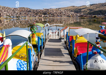 Tier-förmigen Tretboote oder Tretboote in Puno am Titicacasee mit Stadt Puno im Hintergrund, Peru Stockfoto