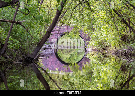 In Beavermead Park, Peterborough, Ontario, eine steinerne Brücke mit einem 180°-Bogen ist sehr schön in einem kleinen Zweig des Otonabee river nieder. Stockfoto