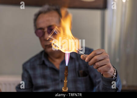 Nahaufnahme Makro von Glas Gebläse arbeiten mit Flamme auf einen handgemachten Glas Wein aus kostbaren Kristall in einer Werkstatt. Konzept der handgefertigten, hohe Qualität, Kunst Stockfoto