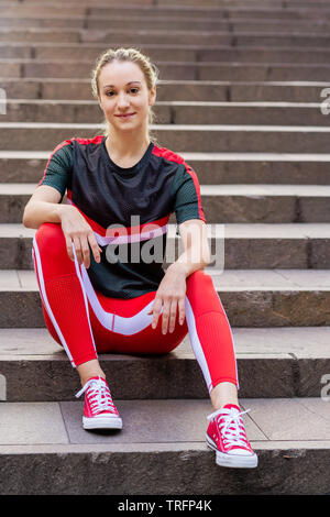 Fit und Aktiv junge Frau in der Stadt, sie erstreckt sich auf einige Treppen Stockfoto