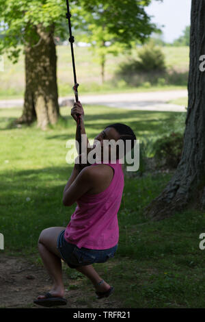 Eine hübsche junge Mädchen Spaß haben Schwingen am Seil schwingen in der Nähe von Spencerville, Indiana, USA. Stockfoto