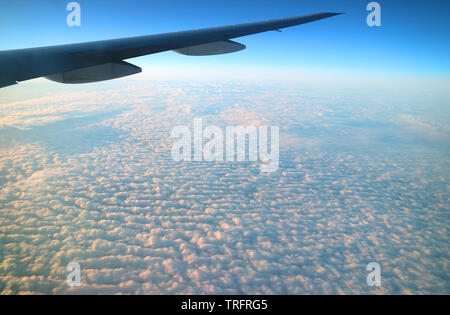 Beeindruckende Sicht auf die Flügel eines Flugzeugs über den Wolken aus dem Flugzeug Fenster während des Fluges gesehen Fliegende Stockfoto