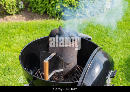 Rauchen Holzkohle Chimney Starter für Grill. Stockfoto