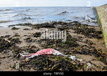 DAUGAVGRIVA, Lettland. 1. Juni 2019. Plastikbeutel liegend auf Sand am Strand in der Nähe von Ostsee. Stockfoto