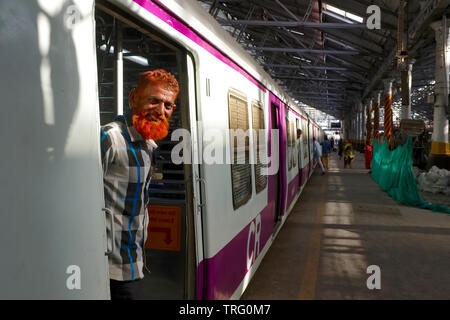 Ein muslimischer Mann mit hennafarbenem Bart und Haar, der vor der Tür eines Surburbanzugs am Chhatrapati Shivaji Maharaj Terminus in Mumbai, Indien, stand Stockfoto