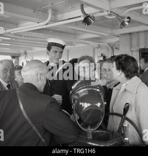 1950, historische, glücklich Kreuzfahrtpassagiere stand neben einem uniformierten Seemann an Bord der P&O Versand, SS Chusan, einer britischen Ocean Liner. Stockfoto