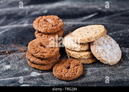 Chocolate Chip und Hafer frische Cookies mit Zucker Pulver Stacks auf schwarzem Hintergrund. Stockfoto