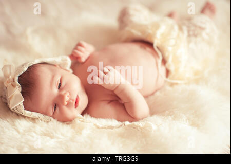 Cute Baby Mädchen liegt im Bett Nahaufnahme. Stilvolle Kleidung tragen. Kindheit. Stockfoto