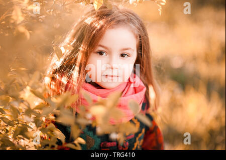 Blond stilvolle kid Mädchen 3-4 Jahre alten tragen Schal und Jacke posiert im Freien. Mit Blick auf die Kamera. Kindheit. Herbst Saison. Stockfoto