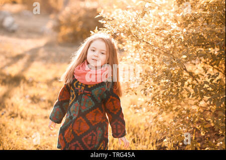 Lustige stilvolle Baby Mädchen 4-5 Jahre alten das Tragen modischer Wintermantel walking im Park. Bei Kamera schaut. Glück. Kindheit. Stockfoto