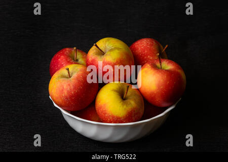 Stillleben rote Äpfel Natur Morte aus roten Äpfeln in weißer Schüssel auf schwarzem Hintergrund. Stockfoto