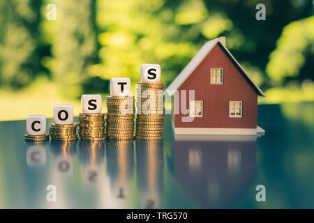 Symbol für steigende Haus kosten. Würfel Form kosten das Wort ' ' auf die Steigerung der hohen Stapel von Münzen. Stockfoto