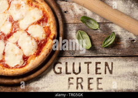 Eine glutenfreie Pizza auf eine rustikale Holz Hintergrund, in der Nähe Stockfoto