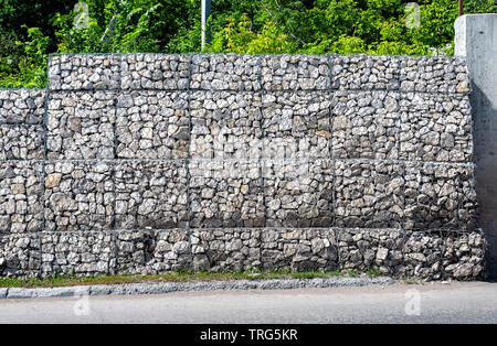 Schutz Zaun oder Mauer aus gabionen mit Steinen. Steinmauer mit Metallgitter als Hintergrund. Stein -Textur Stockfoto