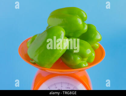 Grüner Pfeffer auf Skalen, die auf blauem Hintergrund Stockfoto