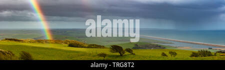 Ein Regenbogen über Abbotsbury, Chesil Beach und Portland, Jurassic Coast, Dorset, England. Stockfoto