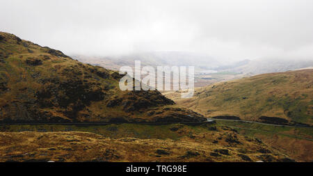 Atemberaubende Landschaft mit Nebel und Moody skies unter schönen Berge - während einer Wanderung am Snowdon im Winter gefangen (Snowdonia National Park, Wales, Stockfoto