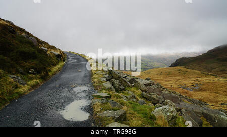 Stein Weg entlang ein beeindruckender Aussicht, durch gesättigte Gras, schönen Berge und einem nebligen Himmel - während einer Wanderung am Snowdon im Winter gefangen umgeben ( Stockfoto