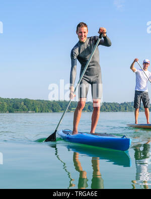 Zwei stand up Paddler anjoying Morgensonne auf einem See in Bayern Stockfoto