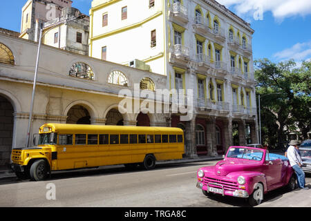 Havanna, Kuba - 30. Januar 2018: Die klassischen, alten gelben Schulbus und einen rosa cabriolet Parken in den Straßen von Havanna Stockfoto