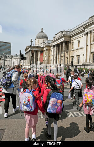 Schüler der Grundschule Mädchen und Jungen mit Disney Rucksäcke die Straße entlang der National Gallery London England UK KATHY DEWITT zu besuchen Stockfoto