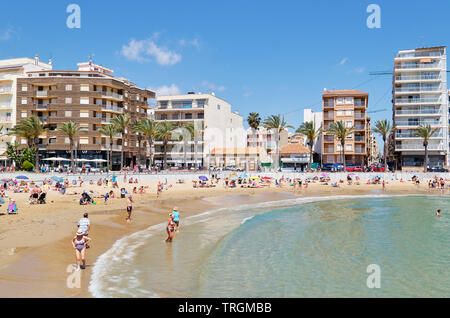 Torrevieja, Spanien - 16. Mai 2019: Menschen Sonnen, Schwimmen am Strand Playa del Cura in Torrevieja Resort City, klare Bucht Wasser im Mittelmeer Stockfoto