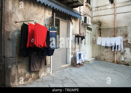 Mehrfarbige gewaschenen Kleider sind auf dem Balkon in der Gasse von Neapel, getrocknet - Catering und Umweltfreundlichkeit, Copyspace Stockfoto