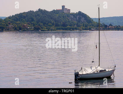 Dämmerung am Lago Maggiore, Segelboot mit Angera Schloss im Hintergrund. Italien Stockfoto