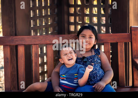 Große Schwester mit Arm um ihren kleinen Bruder, die aufgeregt ist und Geschrei laut. Stockfoto