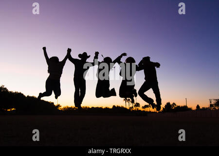 Country Familie im Sonnenuntergang tanzen und springen Stockfoto