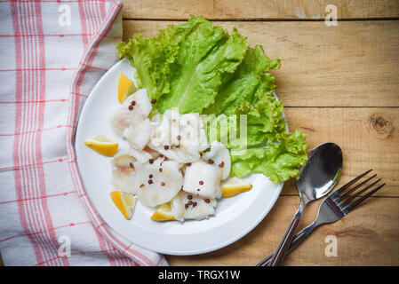 Gekochter Fisch Filet Stück mit Zitrone und Gewürzen auf weiße Platte Holztisch Hintergrund/Pangasius dolly Fisch Fleisch Stockfoto