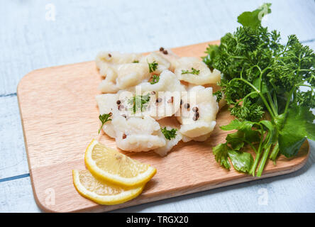 Gekochter Fisch Filet Stück mit Zitrone und Gewürzen auf Holz Schneidebrett Hintergrund/Pangasius dolly Fisch Fleisch Stockfoto