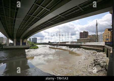 Blick auf den Fluss Lea bei Ebbe von unterhalb der A1020 Flyover in Canning Town, East London, UK. Zeigt Trinity Buoy Wharf über (rechts). Stockfoto