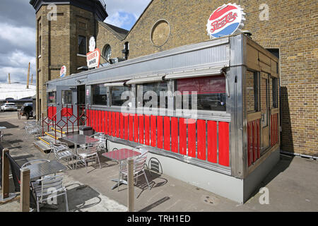 Fat Boys Diner, das Café im amerikanischen Stil in Trinity Buoy Wharf neben der Themse in London, Großbritannien. Zeigt den Leuchtturm des Trinity House. Stockfoto