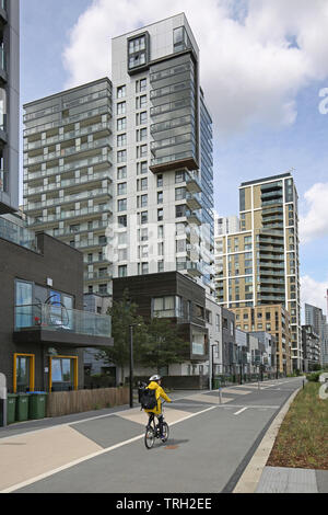 Ein Radfahrer übergibt Riverside Apartment Blocks auf der London Greenwich Peninsula, eine neue Wohnsiedlung von Chinesischen Entwickler Ritter Drachen. Stockfoto