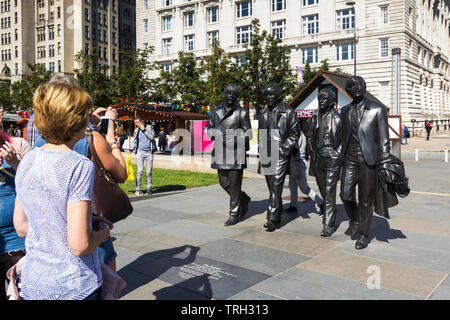 Touristen Anzeigen der Beatles Statue auf Liverpools Pier Head. Die Statue wurde im Dezember 2015 vorgestellt und war ein Geschenk an die Stadt durch den Cavern Club. Stockfoto