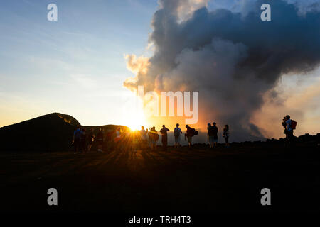 Touristen zu Fuß auf den Kraterrand des Rauchens Mt Yasur Vulkan bei Sonnenuntergang, Insel Tanna, Vanuatu Stockfoto