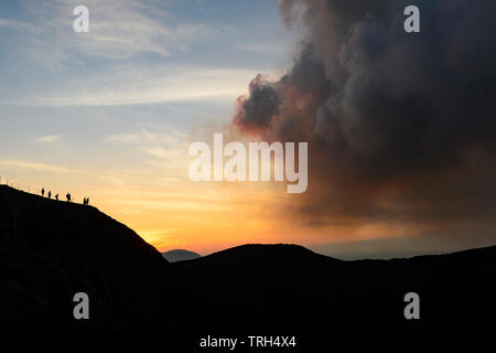 Silhouetten von Touristen zu Fuß entlang der Kraterrand Pfad, Mt Yasur Vulkan bei Sonnenuntergang, Insel Tanna, Vanuatu Stockfoto