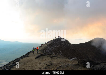 Touristen zu Fuß auf den Kraterrand des Mt Yasur Vulkan bei Sonnenuntergang, Insel Tanna, Vanuatu Stockfoto