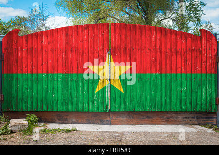 Nahaufnahme der Nationalflagge von Burkina Faso auf einem hölzernen Tor am Eingang des geschlossenen Gebiet an einem Sommertag. Das Konzept der Lagerung von Gut Stockfoto