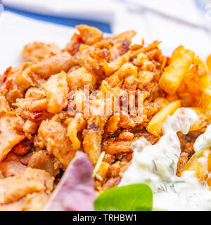 In der Nähe von Tomaten, Oliven, Feta Käse und gebratenem Fleisch Stücke von einer berühmten griechischen Gericht, gegen einen verschwommenen Hintergrund. Blick auf den Platz Stockfoto