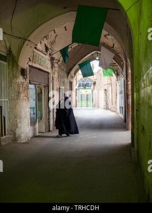 Eine Dame trägt einen tschador Spaziergänge durch eine Gasse in Kashan, Iran. Kashan ist eine der ältesten bewohnten Städte im Iran, zurückgehend auf Pre-Historica Stockfoto